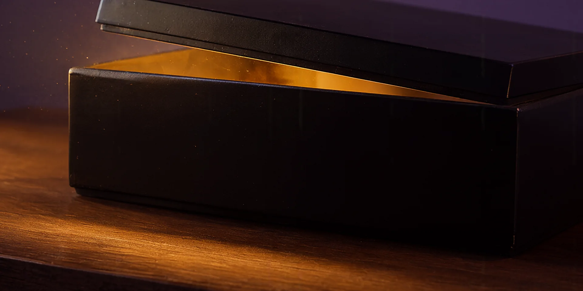 Una caja negra lacada sobre la mesa, con la tapa entreabierta; por la rendija escapa una luz dorada.