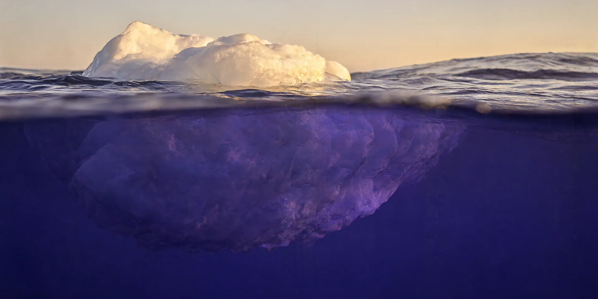 Un iceberg : au-dessus de l'eau, seule la pointe éclairée ; en dessous, l'énorme masse invisible depuis la surface.