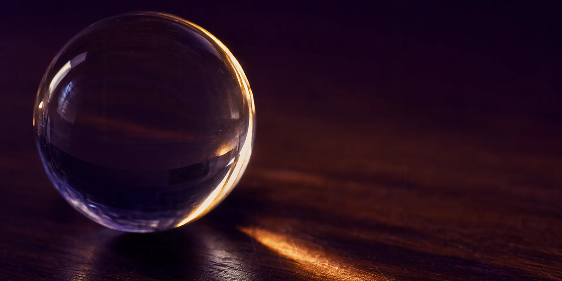 Une sphère de verre presque invisible dans l'obscurité, révélée seulement là où la touche un rai de lumière ambrée.